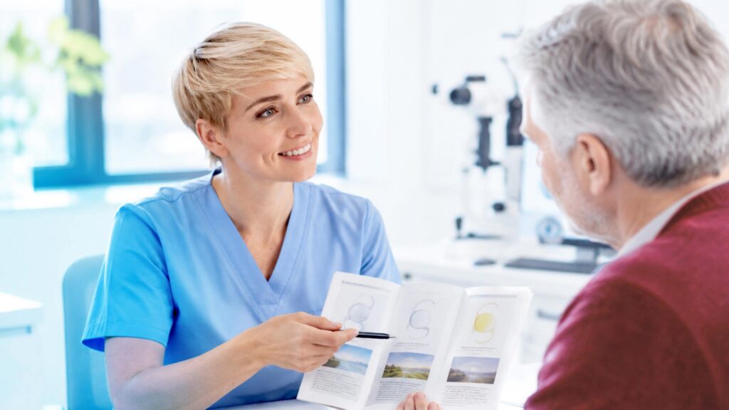 Eine Medizinische Fachkraft zeigt einem Patienten eine Broschüre über Kunstlinsen.
