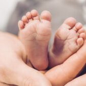 Hebamme hält Füße eines Neugeborenen